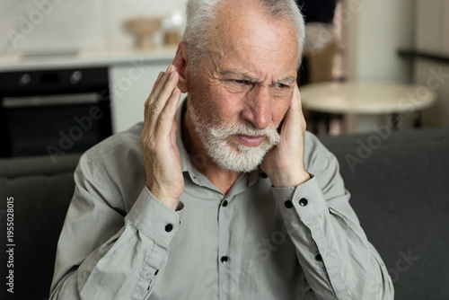 Senior man suffering ear infection and headache at home