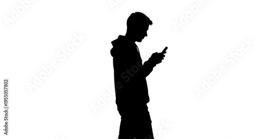 Silhouette of a young man walking and using a smartphone