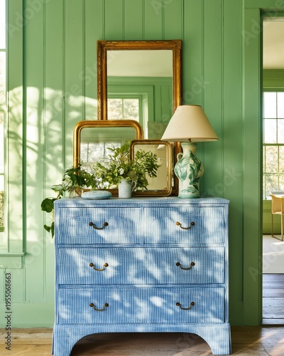 Vintage dresser with blue gingham pattern and brass handles positioned against a green wall, adorned with mirrors and a lamp, showcasing a bright interior design