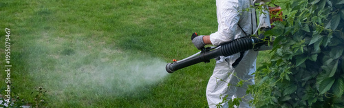 Spring garden pest control: man in protective suit spraying plants. banner