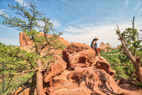 Hiker rests atop rugged red rock formation