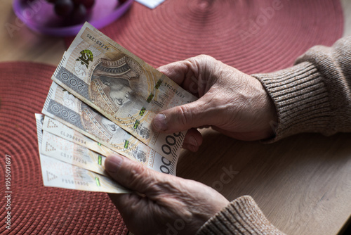 Photos A senior, an elderly person, holds Polish money in his hands.