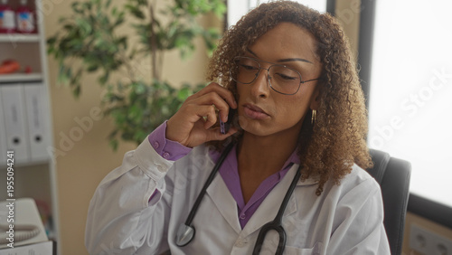 Εκτύπωση καμβά Confident woman in white coat holds phone to ear with stethoscope around her neck in clinic; concentration