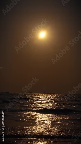Mumbai Maharashtra India Jan 18 2026 Vertical dramatic view of a dark golden sunset over the Arabian Sea with glowing reflections on rolling waves at Juhu Beach.