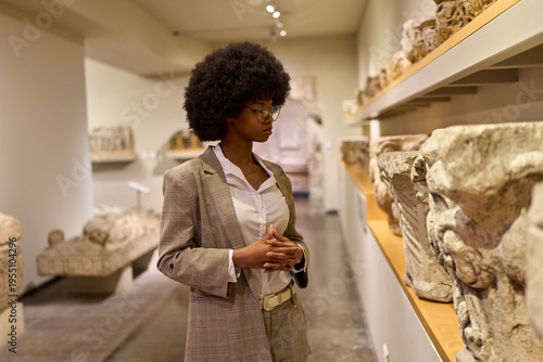 Woman wearing glasses and looking at exhibition. Concept of Museum Day.