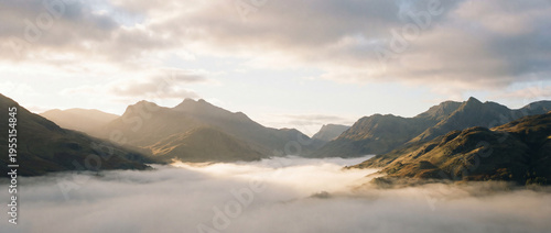 Sun-kissed mountain peaks emerging from a sea of morning clouds, creating a breathtaking and ethereal natural landscape
