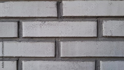 Close-up of white brick wall texture with grey cement mortar joints. Rhythmic pattern of masonry, for architectural backgrounds, construction industry, and urban building facade design projects