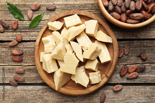 Organic cocoa butter and beans on wooden table, flat lay