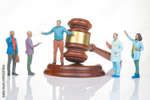 Miniature figurines in a courtroom scene with a gavel and people discussing the law and justice