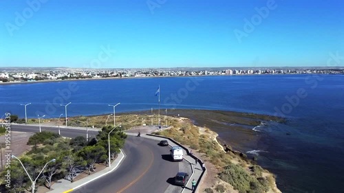 Aerial shot of the city of Puerto Madryn Chubut from the sea. Punta Cuevas, the argentine flag and modern buildings facing Golfo Nuevo are visible.