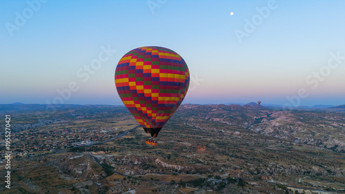 Wallpaper Mural Goreme, Nevsehir, Turkey. Large colorful checkered hot air balloon with big basket and fire bursts flying over plateau with blue haze horizon at sunrise. Aerial View Torontodigital.ca