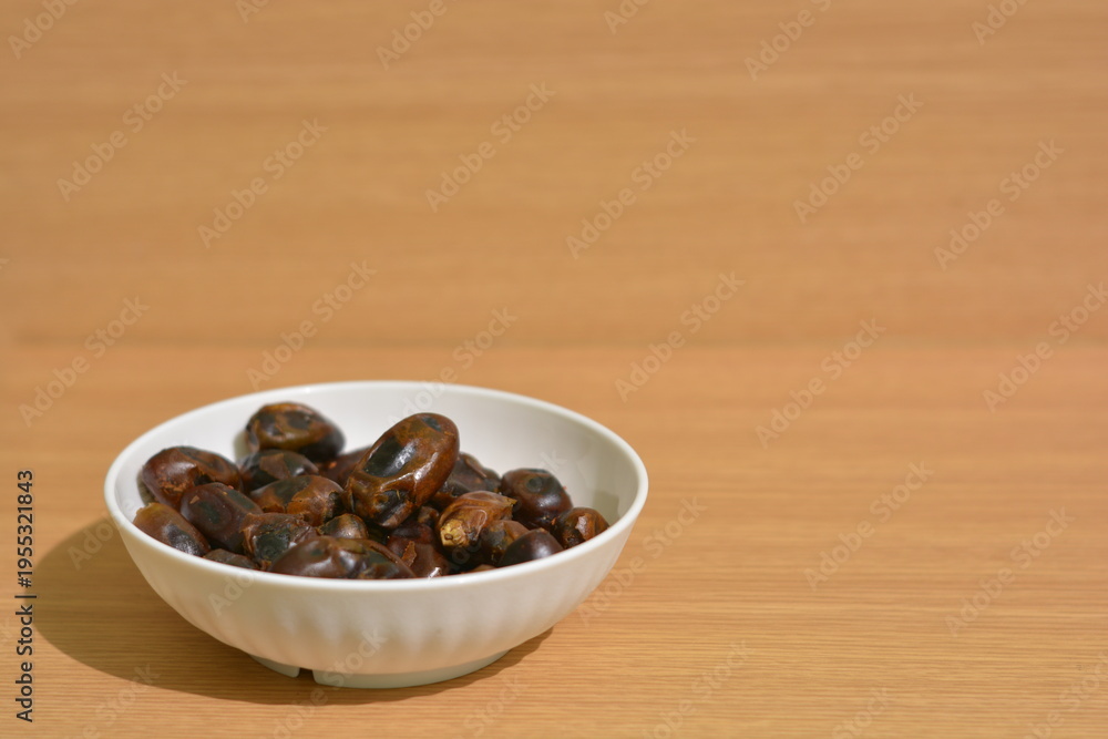 Obraz premium Bowl of dried dates with wide copy space on wooden background