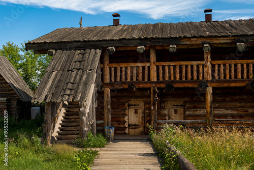 The impressive wooden walls of a reconstructed Old Slavic fortress, made of round, hewn logs. Old barracks and boyar chambers. A bright, sunny day.