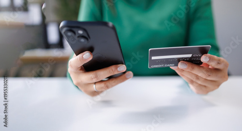 A woman holds a smartphone and a credit card while navigating payment options. This captures the essence of modern financial transactions in everyday life.