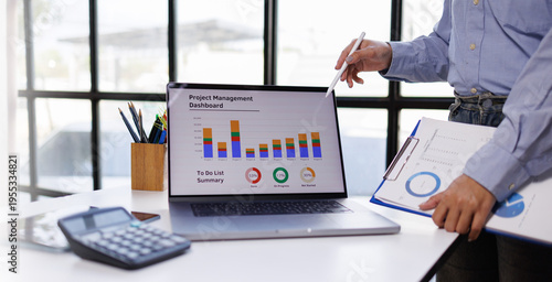 A comprehensive view of a professional reviewing a project management dashboard on a laptop, emphasizing the value of data-driven decision making in teamwork.