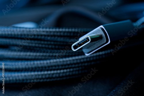 USB‑C plug with visible metal contacts and braided cable texture in selective focus. Concept of digital connectivity, fast charging, and modern electronic devices. Photo