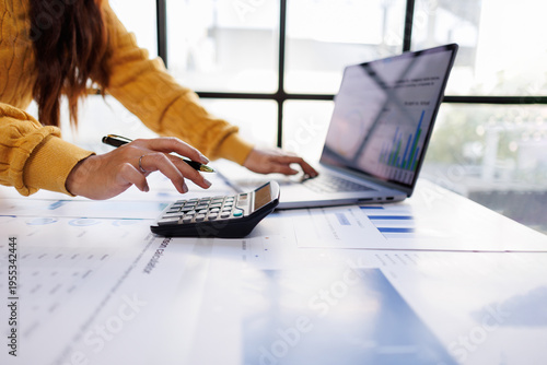 Tableau sur toile A focused individual works with a calculator and laptop while surrounded by printed financial reports, conveying the importance of effective planning and analysis