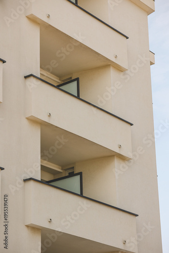 View from below of the facade of a building, close up on the geometrical features of the balconies. Modern residential concrete design.
