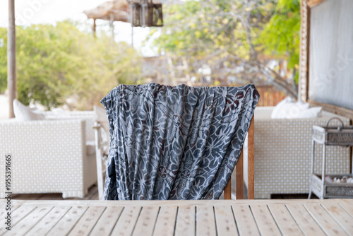 Colorful pareo or sarong left on the back of a chair on the porch of a tropical beach house. Summer vacation mood, carefree, relaxation mood.