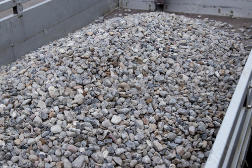 Pile of small gray and white gravel stones loaded in the back of a truck, showcasing various sizes and shapes of aggregate materials for construction use
