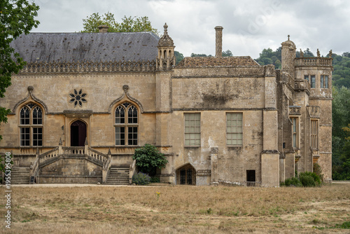 Exterior view of Lacock Abbey's south facade with its ornate windows and staircase, England