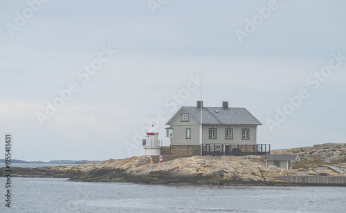 Slika na platnu Remote coastal dwelling with adjacent lighthouse perched on rugged rocky island