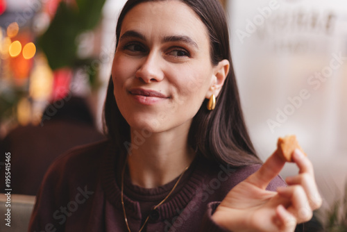 Foto Happy young brunette woman with gold jewelry holding a smaller piece of tasty co