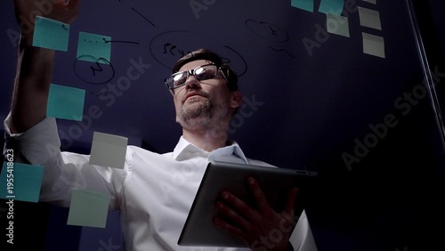Bild auf Leinwand Man in eyeglasses organizing thoughts and ideas for business optimization on a clear glass board