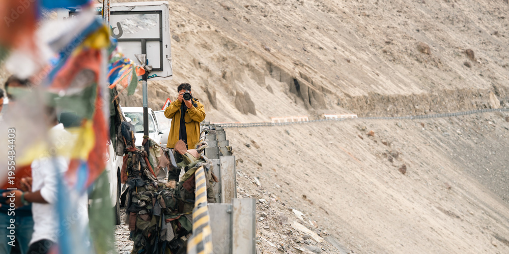 Fototapeta premium Man in brown jacket stands with eyes closed and hands on chest, feeling peaceful in serene landscape of leh ladakh india, popular travel destination for tourist seeking himalayan adventure