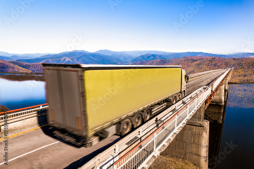 Photos Green truck moving by a bridge over the river