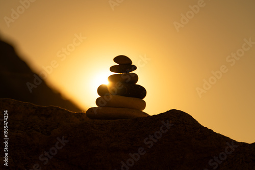 Canvas Print Cairn balance sunset silhouette on rocky surface against vibrant golden sky representing peace spirituality and zen concepts