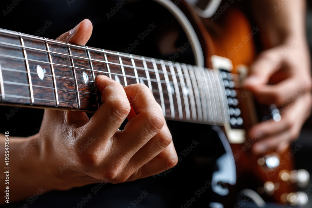 Obraz premium Hands playing guitar with focus on the fretboard and strings in a cozy indoor setting