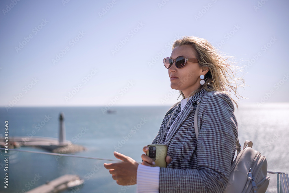 Obraz premium Businesswoman blonde sunglasses seaside view contemplating ocean success on sunny day copy space