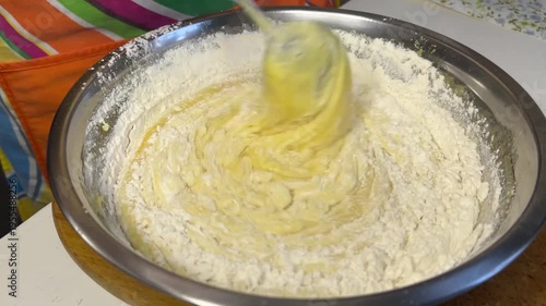 Horizontal side view video of combining mixture with flour and mixing dough for honey cake preparation
