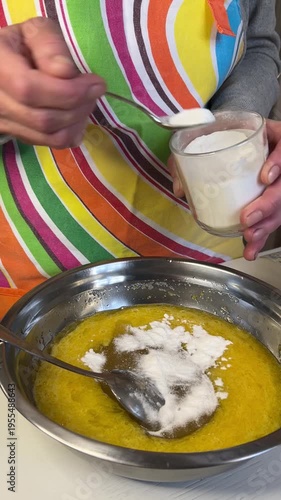 Adding baking soda or baking powder to a honey and butter mixture for honey cake preparation, vertical video, side view