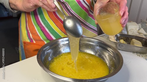 Adding honey to the mixture for honey cake, horizontal video, side view; butter visible on the table in the background