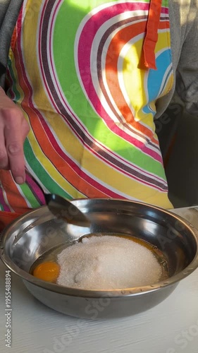 Adding sugar to eggs and mixing the mixture for dough preparation, vertical video, side view