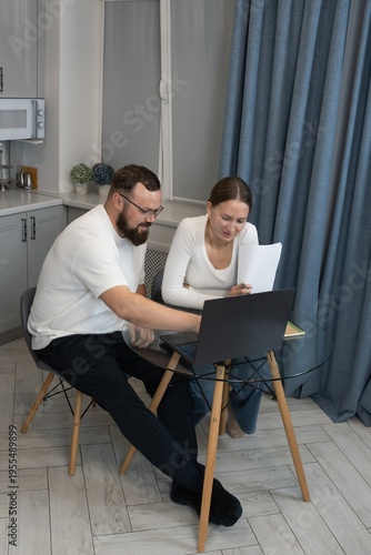 Couple managing home finances using laptop and documents