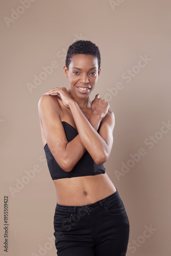 Beautiful confident Black woman with short natural hair posing in studio on beige background