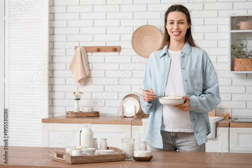 Young pregnant woman with different dairy products at table in kitchen