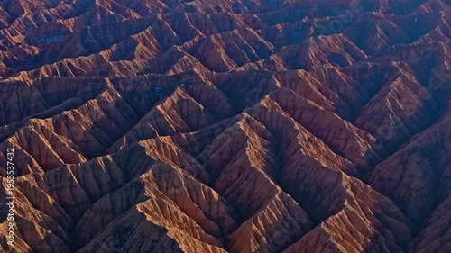 Aerial view captures stunning Ak-Say canyons along Issyk-Kul lake. Eroded landscape showcases unique geological formations during golden hour.