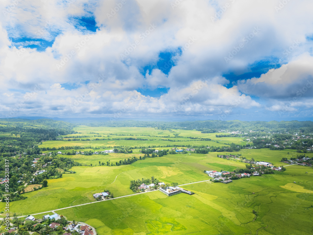 Obraz premium Waikabubak is the capital of West Sumba Regency, encircled by rice fields as seen from the hills, with the rice already turning yellow, awaiting the harvest