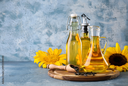Obraz na plátně Wooden tray, bottles of sunflower oil and scoop of seeds on blue grunge backgrou