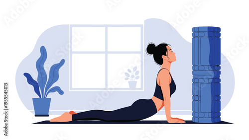 Young woman practicing cobra yoga pose on a mat in a bright minimalist room with an indoor plant and a large blue foam roller.