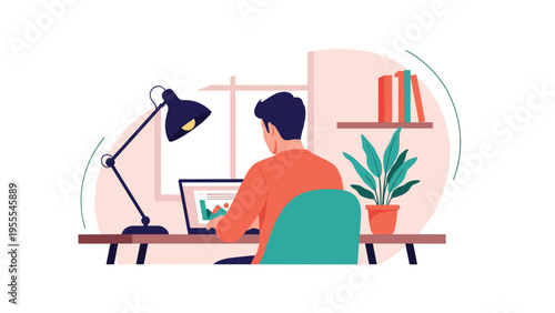 Focused young man works on his laptop at a tidy wooden desk equipped with a reading lamp and a potted plant in his home office during the day.
