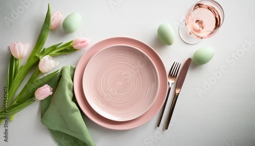 Top view of empty pale pink ceramic plate and green napkin and easter egg decoration on white background with pink tulip flowers. Easter concept