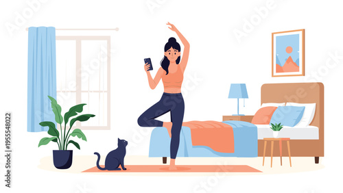 Young woman practicing tree pose yoga in her bedroom while following an online tutorial on her smartphone with a cat nearby.