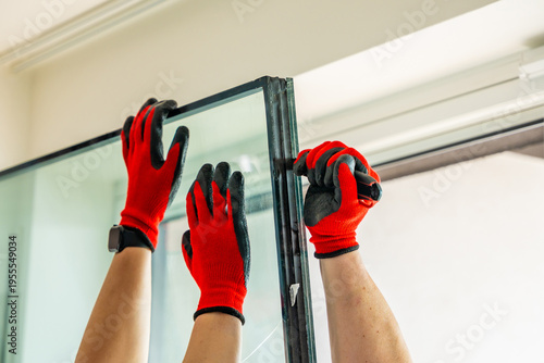 Worker separating triple glazed window glass unit into individual panels for safe handling and disposal after damage in apartment. Window repair, glass recycling and maintenance process concept.