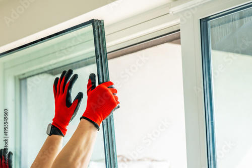Removed triple glazed window glass unit leaning near frame after replacement in apartment. Broken insulated glass panel removal and window repair process concept.