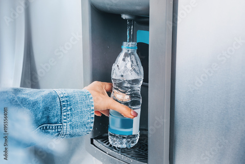 Fotografía Person's hand holding a recyclable plastic bottle, filling it with clean drinkin